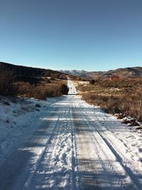 Road amidst snow covered land against sky