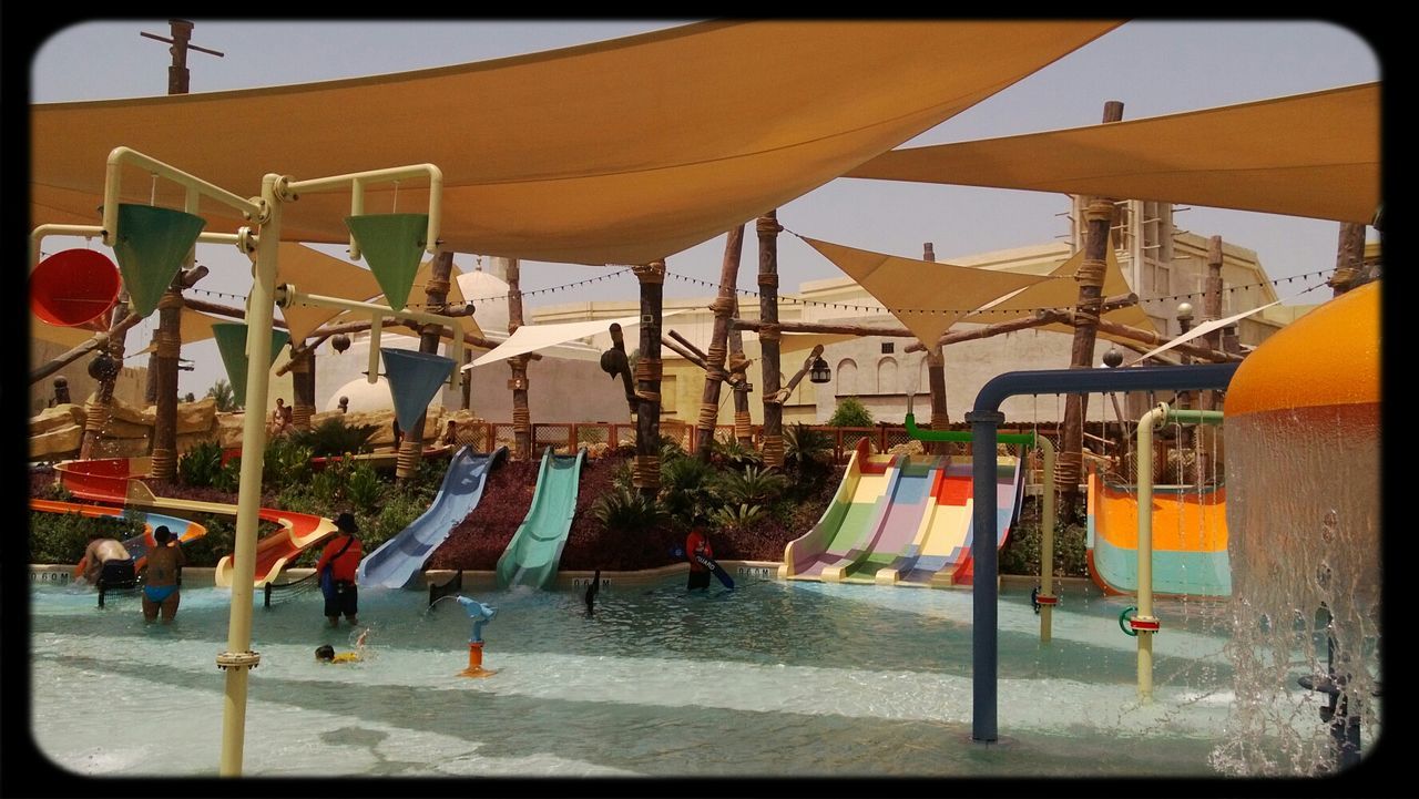 built structure, building exterior, architecture, hanging, flag, beach, sky, parasol, day, outdoors, sand, sunlight, chair, umbrella, incidental people, multi colored, sunshade, drying, men, large group of people