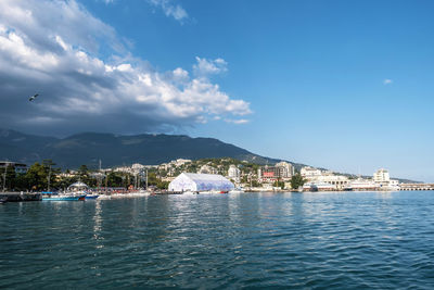 Scenic view of sea by buildings against sky