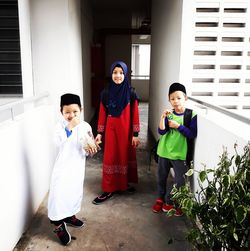 Portrait of siblings standing in corridor of building