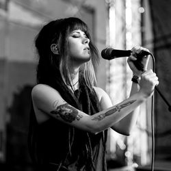 Side view of young woman singing by microphone