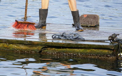 Low section of person cleaning pier with brush