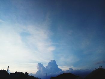 Low angle view of silhouette mountains against blue sky