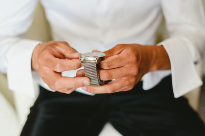 Midsection of man holding wristwatch