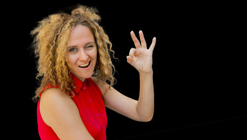 Portrait of smiling young woman looking away against black background