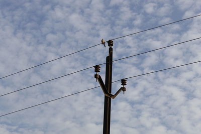 Low angle view of power lines against cloudy sky