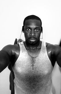 Portrait of muscular man listening music against wall