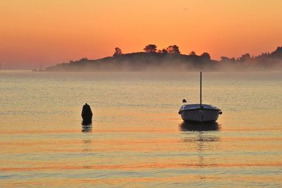 Boat in sea against sky during sunset