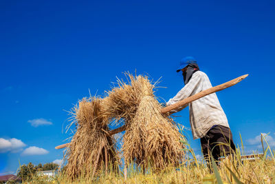 Man working on field against blue sky