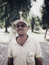 Portrait of man wearing sunglasses standing against trees