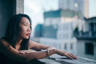 Young woman looking away while sitting outdoors