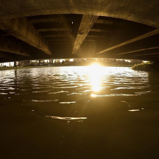 water, reflection, built structure, bridge - man made structure, connection, architecture, waterfront, transportation, river, rippled, sunlight, engineering, illuminated, bridge, no people, indoors, below, diminishing perspective, architectural column