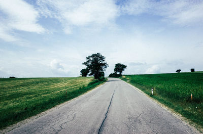 Road amidst agricultural field against sky