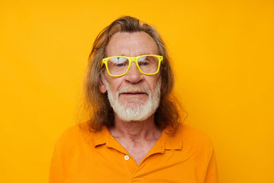 Portrait of senior man against yellow background