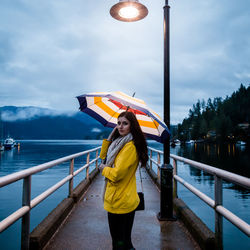 Full length of woman standing on railing against sky