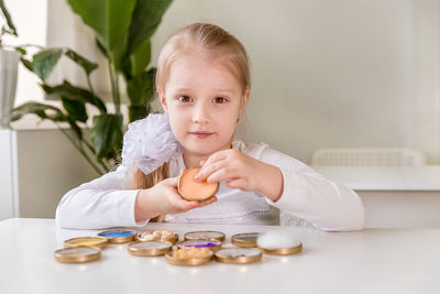 A girl student sits at a desk in the classroom and collects figures / puzzles / small toys 