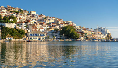 Townscape by sea against clear blue sky