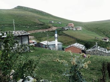 Houses on field by mountain against sky