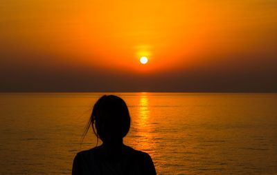 Rear view of silhouette woman against sea during sunset