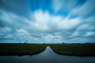 Panoramic view of road amidst field against sky