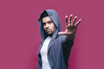 Portrait of young man standing against red background