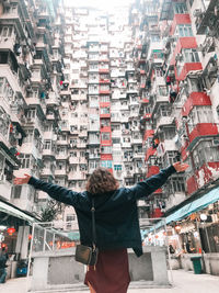 Rear view of man standing by buildings in city