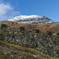 Stone wall by mountain against sky