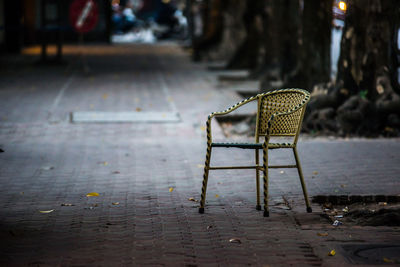 Empty chair on footpath in city