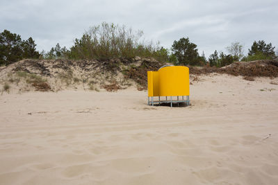 Lifeguard hut on desert land against sky