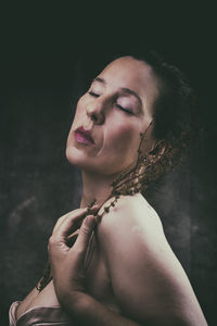 Portrait of young woman against black background