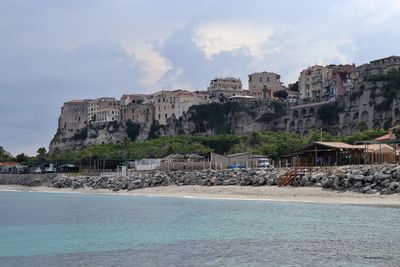 Buildings by sea against sky