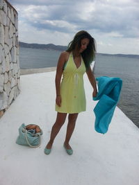 Young woman with textile standing on pier by sea