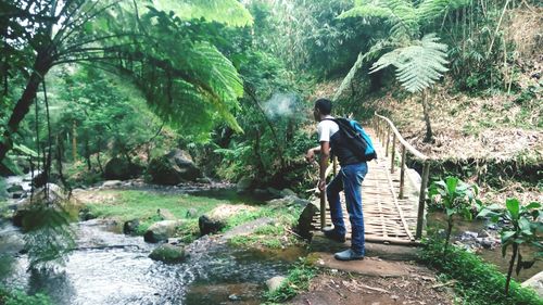 Full length of man carrying backpack standing on footbridge over stream at capolaga nature tourism