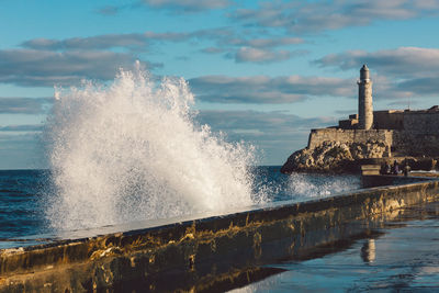 Waves breaking on sea shore against sky