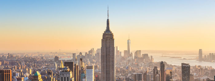 Modern buildings in city against clear sky during sunset
