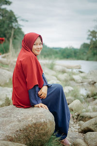 Portrait of young woman sitting on rock