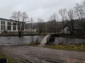 Canal amidst houses and trees against sky