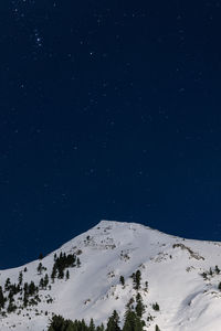 Low angle view of snowcapped mountain against sky at night