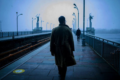 Rear view of man walking on railroad station