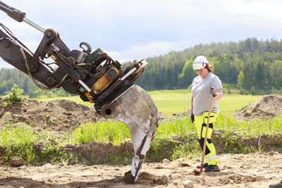 Female worker standing near digger scoop