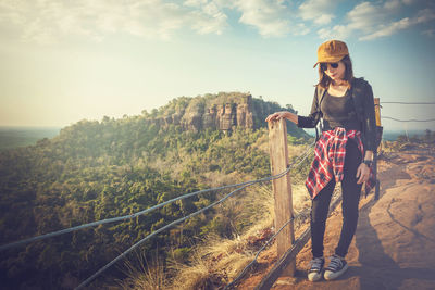 Young woman standing on mountain against sky