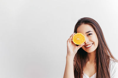 Portrait of young woman holding ice cream against white background