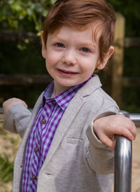 Portrait of cute boy standing on merry-go-round at playground