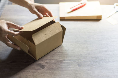 High angle view of hand holding paper box on table