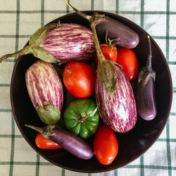 Directly above shot of tomatoes with eggplants and chili peppers in bowl