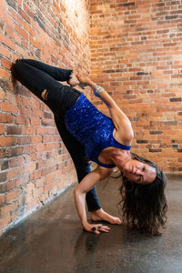 Woman with arms outstretched against brick wall