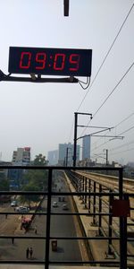 Information sign at railroad station in city against sky