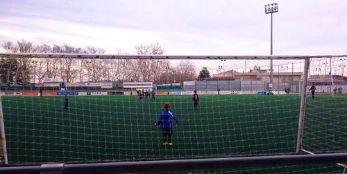 People playing soccer on field against sky
