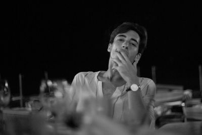 Portrait of young man looking away while sitting at a table smoking a cigarette