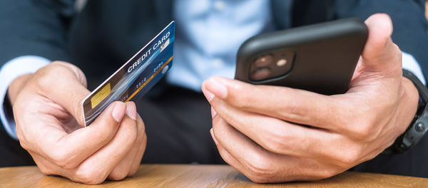 Midsection of man using mobile phone on table